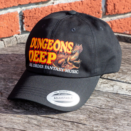 A black dad hat embellished with the Dungeons Deep Records "Mail Order Fantasy Music" Dragon emblem on a wooden backdrop.