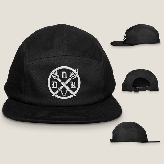 A black brushed cotton canvas camper style cap with a curved bill, featuring a white logo of crossed torches on the front. Shows front, back and side hat profiles.