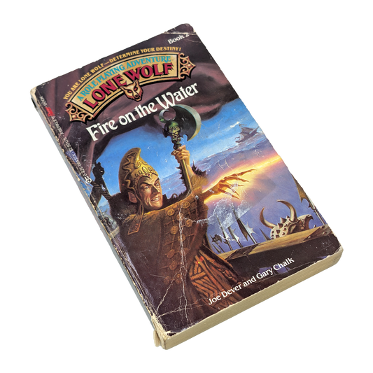 A vintage paperback book of the Lone Wolf series, titled 'Fire on the Water', shown at an angle on a plain white background. The cover features a detailed fantasy illustration of a warrior holding a spear.