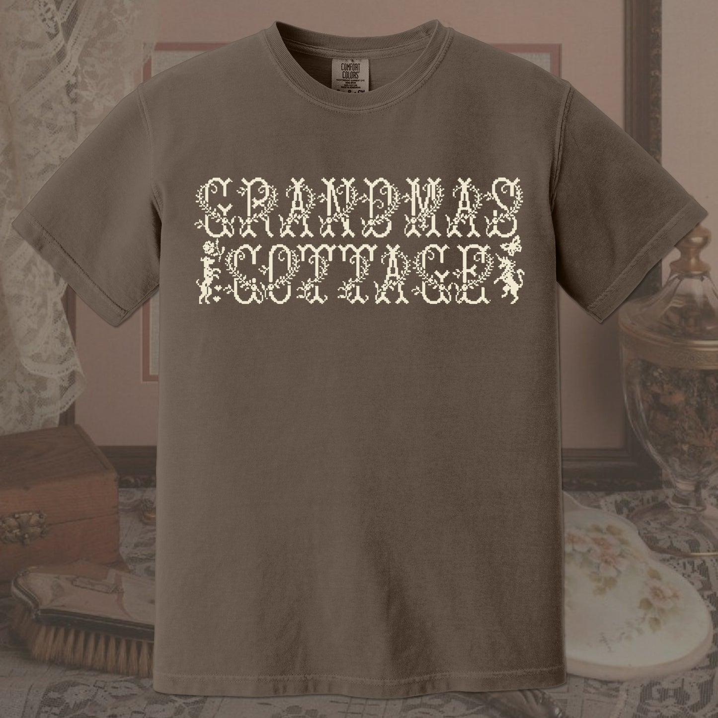 Brown t-shirt with 'GRANDMA'S COTTAGE' text in a decorative font on a vintage background.