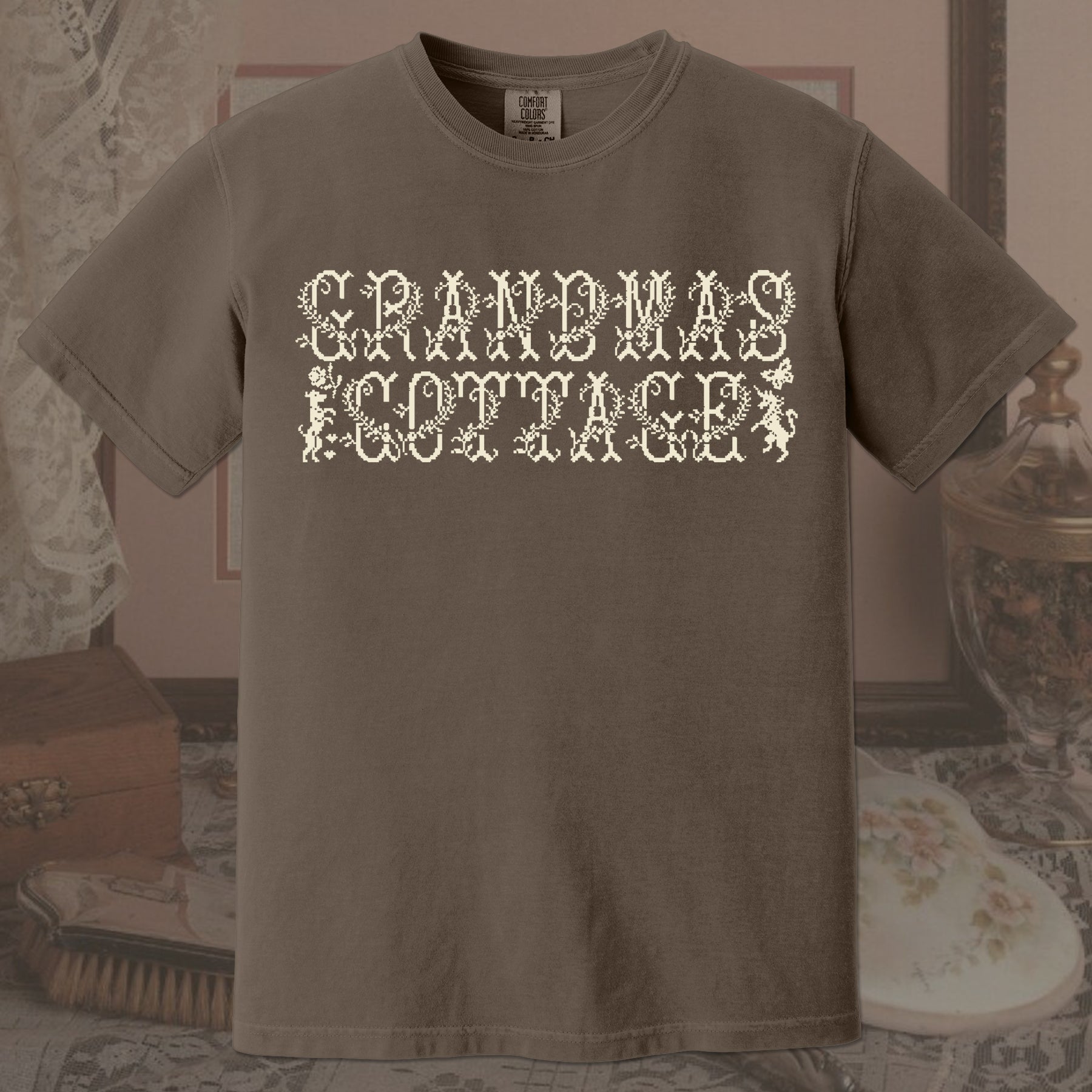 Brown t-shirt with 'GRANDMA'S COTTAGE' text in a decorative font on a vintage background.