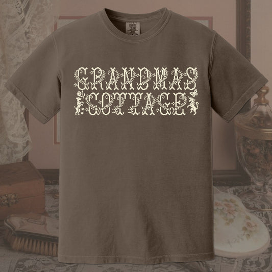 Brown t-shirt with 'GRANDMA'S COTTAGE' text in a decorative font on a vintage background.