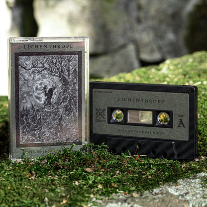 A cassette tape and its plastic jewel case standing outdoors on mossy ground, with a blurred natural stone background. The product branding reads LICHENTHROPE, and the cover art shows a dark monochrome illustration.