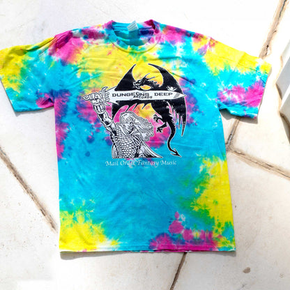 A rainbow tie dye shirt featuring 'Mail Order Fantasy Music' text and illustrations screen printed on the front. The design depicts a man holding a sword with the words "Dungeons Deep Records" inscribed next to a fantasy dragon.