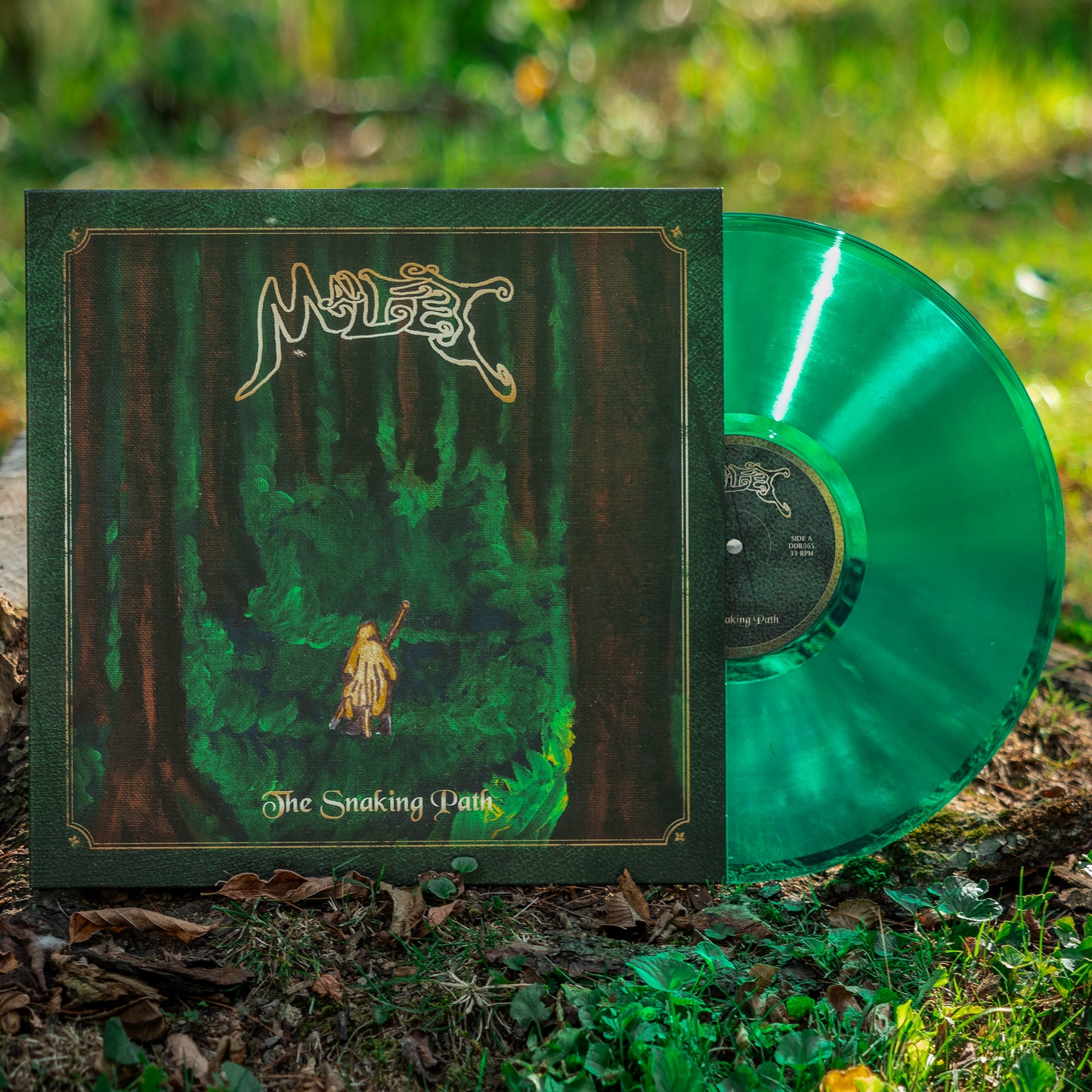 An emerald green vinyl of Malfet's the Snaking Path sits on a grassy gnoll.