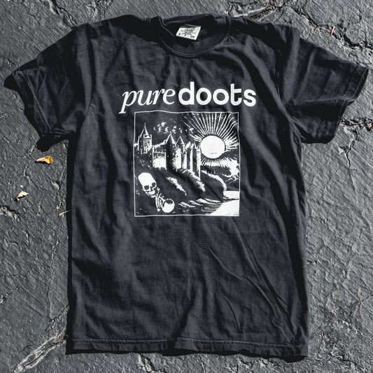 A black T-shirt with the text 'PUREDOOTS' and a screen printed design featuring a castle, moon, and skull on the front.