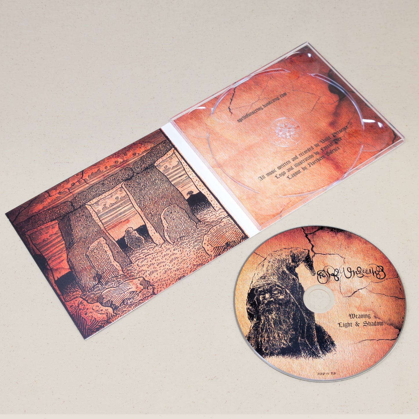 A CD of Spell of Unseeing's Weaving Light and Shadow sitting next to the covering featuring an illustration of a druid. The CD case is laid open to display graphics of a druid temple.