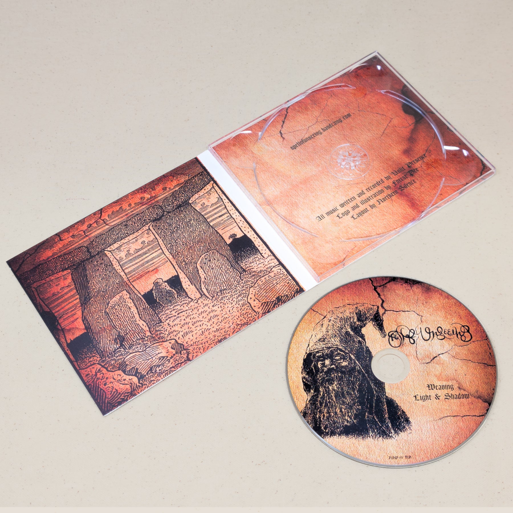 A CD of Spell of Unseeing's Weaving Light and Shadow sitting next to the covering featuring an illustration of a druid. The CD case is laid open to display graphics of a druid temple.