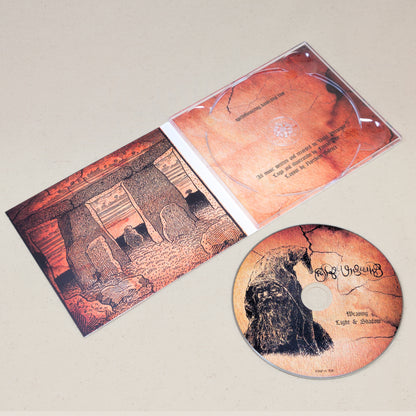 A CD of Spell of Unseeing's Weaving Light and Shadow sitting next to the covering featuring an illustration of a druid. The CD case is laid open to display graphics of a druid temple.