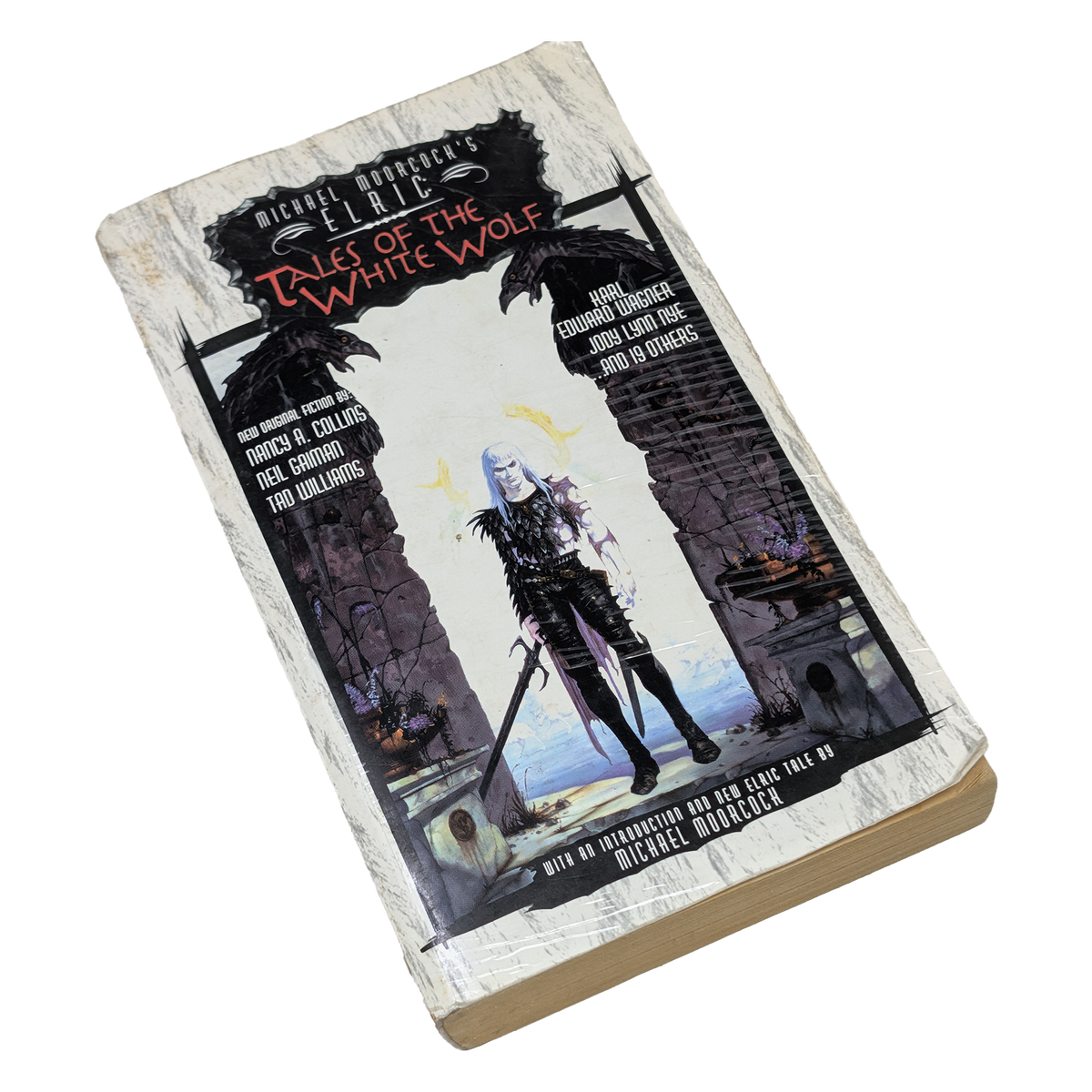 A hardcover book titled 'Tales of the White Wolf' by Michael Malbon, shown at an angle on a plain white background. The cover features a dark fantasy illustration of a masked figure between stone pillars, with the title in red and white lettering.